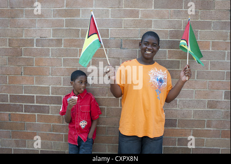 USA : Brooklyn, New York : 2012 West Indian/Caraïbes Kiddies parade. Deux vagues garçon Guyanes drapeaux, Crown Heights. Banque D'Images