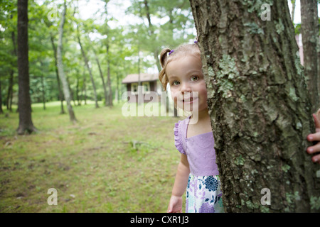 Jeune fille se cacher derrière tree Banque D'Images