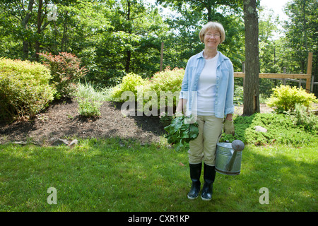 Femme avec arrosoir et betteraves dans jardin Banque D'Images