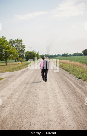 Businessman walking loin vers le bas une route de terre Banque D'Images