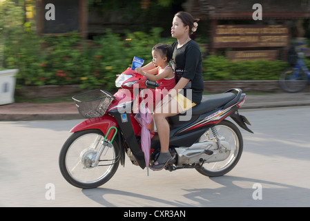 Une mère et sa fille dur passé sur une moto à Luang Prabang, Laos Banque D'Images