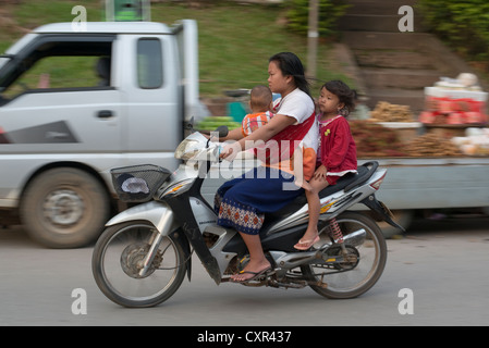 Une mère et ses deux enfants passent sur une moto à Luang Prabang, Laos Banque D'Images