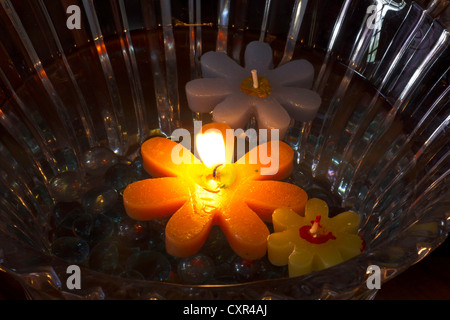 Aides flottantes bougie dans un bol en verre, remplir d'eau. La flamme de l'une des bougies était sorti, mais un plus gros était à la flamme. Banque D'Images