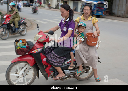 Deux femmes et un enfant passer par sur une moto à Luang Prabang, Laos Banque D'Images