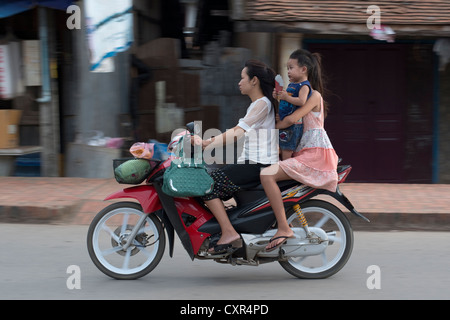 Une mère et ses deux enfants passent sur une moto à Luang Prabang, Laos Banque D'Images