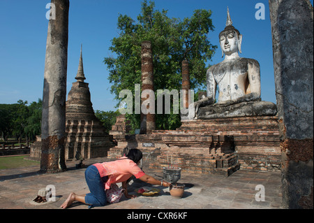 Joss sticks éclairage femme, statue de Bouddha, Wat Mahathat, Parc historique de Sukhothaï, Sukhothai, Thaïlande, Asie Banque D'Images