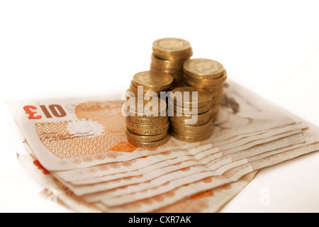 L'une pièces livre empilés sur des notes de dix livres, monnaie, argent sur fond blanc Banque D'Images