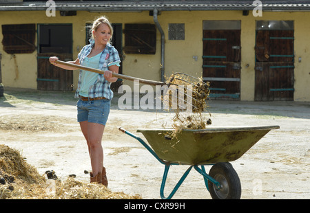 Young female farmer, Pitchfork, le fumier de cheval, curage, push cart, brouette, Gingen, Bade-Wurtemberg, Allemagne, Europe Banque D'Images