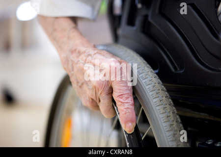 Une femme âgée, vue détaillée de la part du déplacement d'un fauteuil roulant, à une maison de soins infirmiers Banque D'Images