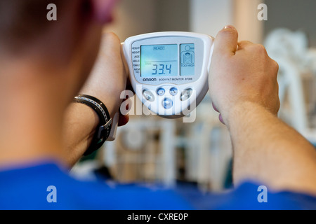 L'homme la mesure de sa masse corporelle, IMC, avant une séance d'entraînement au centre de remise en forme, Regensburg, Bavière, Allemagne, Europe Banque D'Images