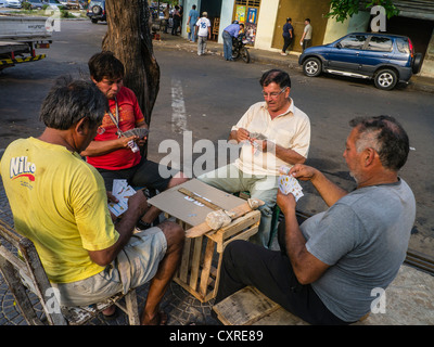 Quatre hommes adultes âgés de jouer à un jeu de cartes sur un trottoir à Asunción, Paraguay. Banque D'Images