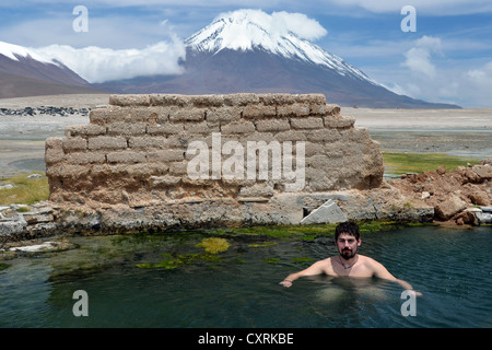 Tourist prendre un bain dans une source thermale à 4800m d'altitude, laguna verde, le volcan Licancabur au dos, de l'altiplano bolivien Banque D'Images