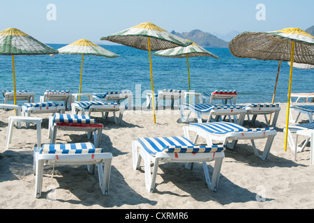 Des chaises longues et des parasols sur la plage de sable d'osier Banque D'Images