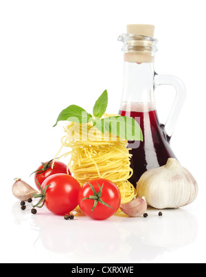 Les pâtes italiennes, tomates cerises, bouteille de vinaigre avec l'ail et basilic isolé sur fond blanc Banque D'Images