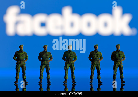 Une rangée de soldats, figures miniatures debout devant un logo Facebook brouillée, image symbolique Banque D'Images