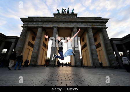 Sautant de joie, deux filles sautant en l'air devant la porte de Brandebourg, Berlin Banque D'Images