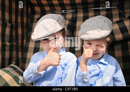 Des jumeaux, 4, portant des bouchons plats Banque D'Images