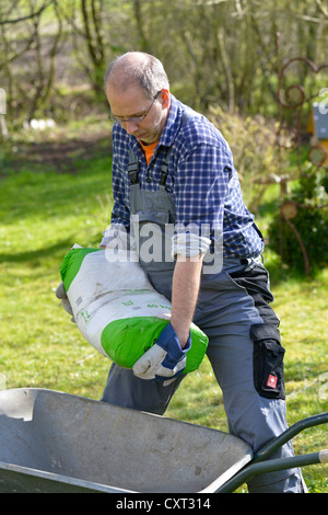 Homme portant un sac de ciment, 40 kg Banque D'Images