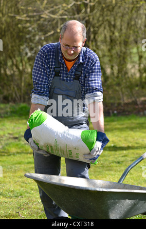 Homme portant un sac de ciment, 40 kg Banque D'Images