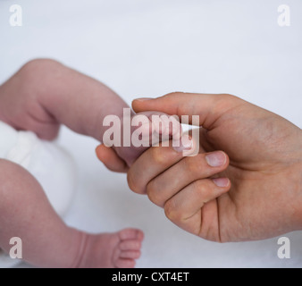 Père tenant les pieds d'un bébé nouveau-né dans ses mains Banque D'Images