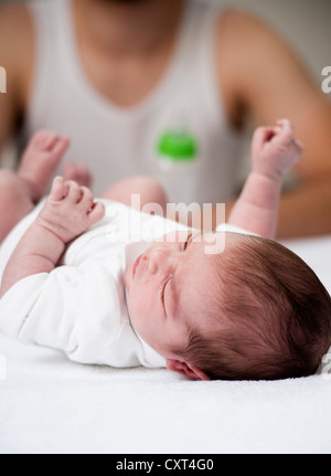 Père tenant une bouteille de lait dans sa main devant son nouveau-né allongé sur une table à langer Banque D'Images