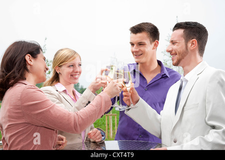 Un groupe de jeunes gens boucher verres, célébrant sur une terrasse Banque D'Images