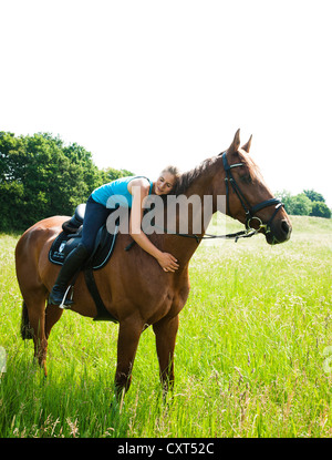 Smiling girl couchée sur le cou de son cheval Banque D'Images