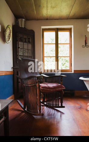 Un fauteuil à bascule et sombre dans la salle à manger d'une ancienne résidence de style cottage Canadiana log home, vers 1840, Banque D'Images