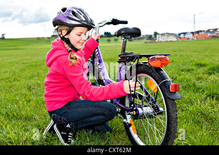 Jeune fille portant un casque de vélo, contrôler son vélo Banque D'Images