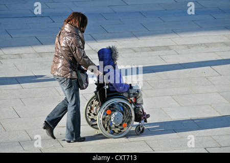 Femme assise dans un fauteuil roulant poussé, PublicGround Banque D'Images