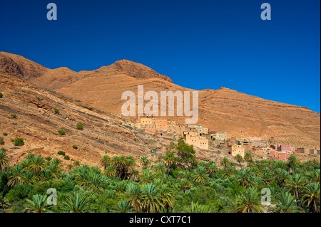 Petit village d'argile sur une pente au-dessus d'une palmeraie dans la vallée Ait Mansour, Anti-Atlas, le sud du Maroc, Maroc Banque D'Images