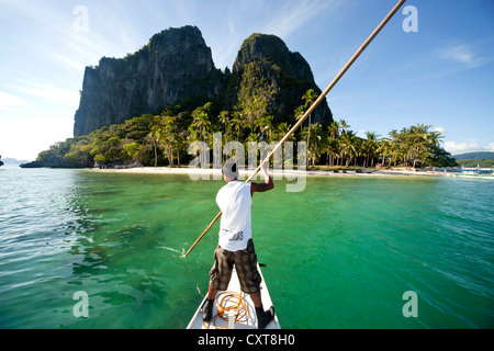 Boatsman dans une approche traditionnelle de l'île en bateau outrigger Inabuyutan, Bacuit Archipelago, El Nido, Palawan, Philippines, Asie Banque D'Images