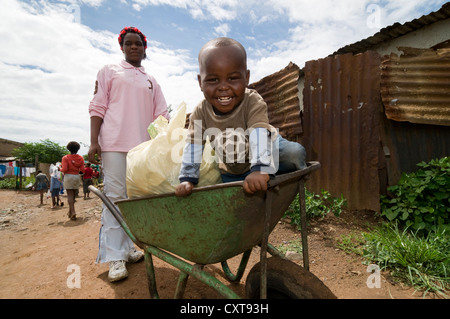 Petit garçon assis dans une brouette service comme un landau, township de Soweto, Gauteng, Afrique du Sud, l'Afrique Banque D'Images