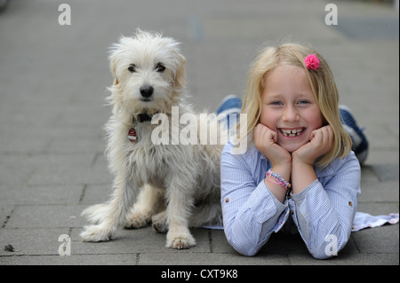 Fille avec un chiot de race mixte située sur un trottoir Banque D'Images