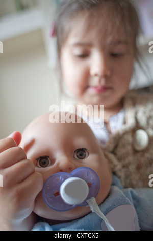 Close up of young girl Playing with doll, focus on foreground Banque D'Images