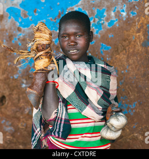 Femme de la tribu-menat tenant une jambe de l'animal, Jemu, vallée de l'Omo, Ethiopie Banque D'Images