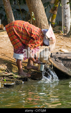 La verticale d'un Indien avec un chapeau de fortune en carton faire leur lessive dans la rivière. Banque D'Images