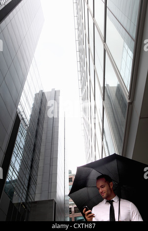 Businessman walking under umbrella Banque D'Images