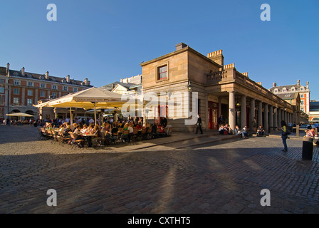 Grand angle horizontal de personnes bénéficiant d'un verre dans le soleil du soir dans l'un des cafés de rue à Covent Garden. Banque D'Images