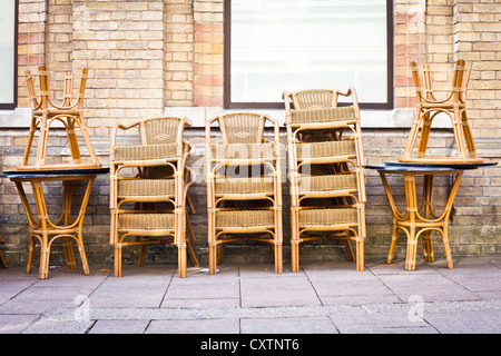 Tables et chaises empilées à l'extérieur d'un café dans une ville Banque D'Images