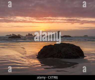 Parc d'état de Bandon, ou : Coucher Soleil nuages et des réflexions à marée basse avec la silhouette du seastacks à Bandon Beach Banque D'Images