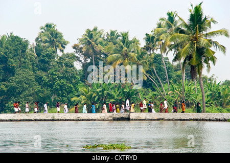 Vue horizontale d'une ligne d'Indiens à marcher le long de la berge, dans le Kerala. Banque D'Images