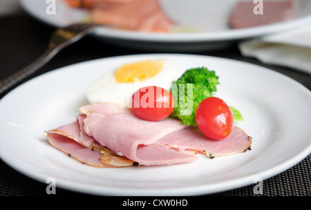 Jambon superposés, un œuf, les tomates et le brocoli frais on white plate Banque D'Images