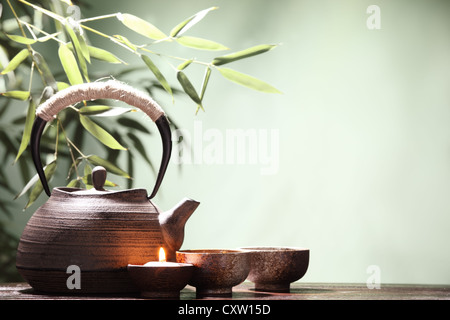 Théière et tasses sur la table avec des feuilles de bambou. Banque D'Images