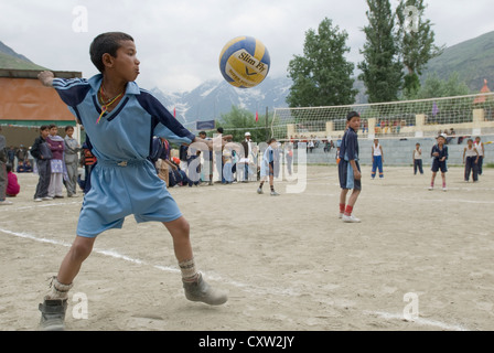 Un garçon sert la balle dans un match de volley-ball garçons Keylong, Inde du Nord Banque D'Images