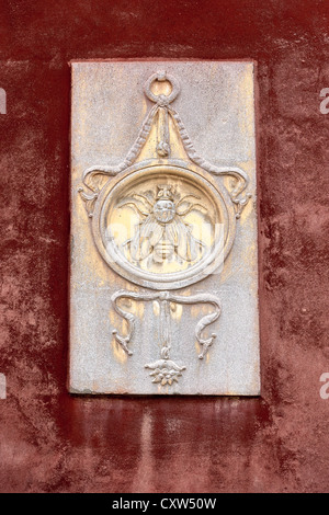 Un symbole ou un emblème sculpté sur le côté d'une maison à Venise représentant une mouche dans un cercle Banque D'Images