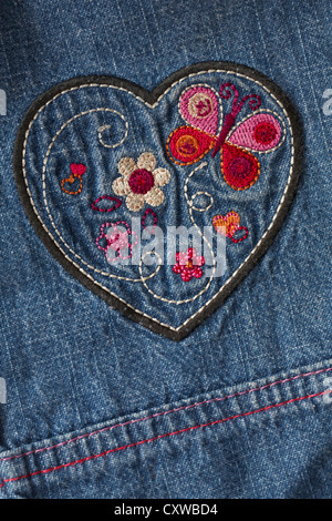 Jolies marguerites et le papillon au coeur brodé sur l'enfant denim jeans Banque D'Images