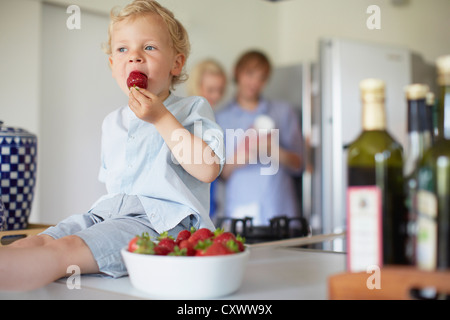 Boy eating strawberries on counter Banque D'Images