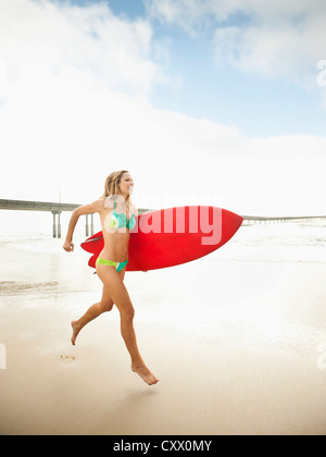 Caucasian woman running with surfboard Banque D'Images