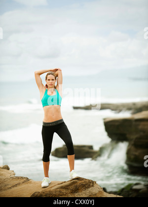 Caucasian woman stretching on rocks near ocean Banque D'Images